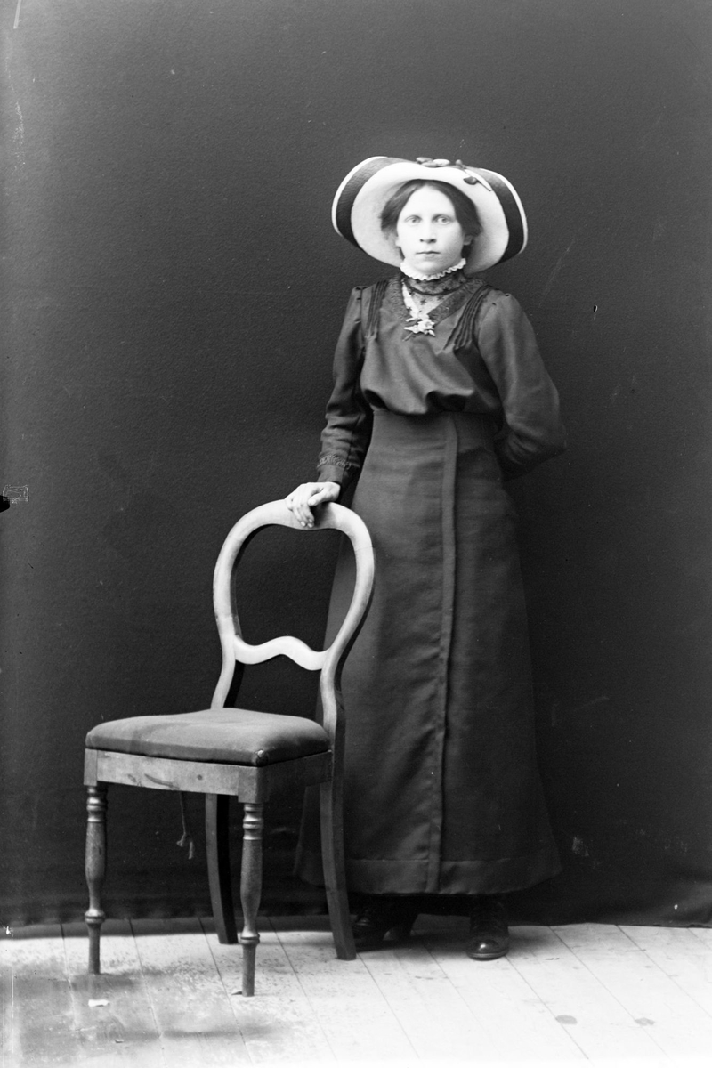 Studioportrett av en kvinne med en stor hatt på hodet.