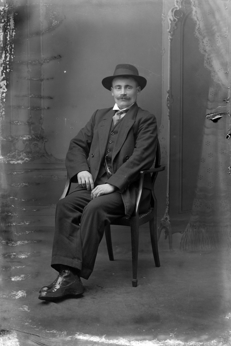 Studioportrett av en mann med hatt.