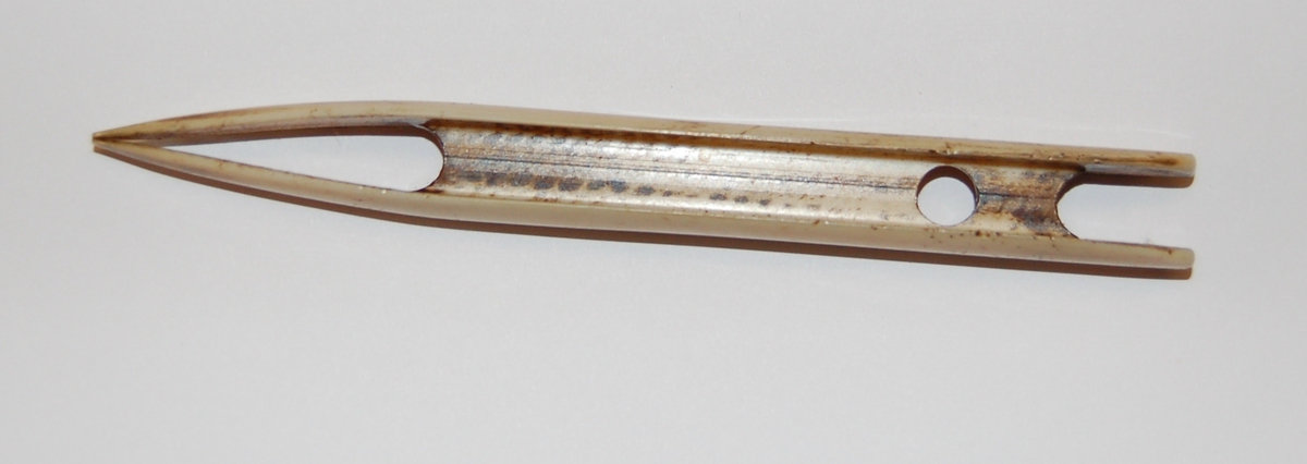 Nålen har en rektangulær form. I nålen er det utfreset et spor som tråden skal spoles opp på, og munnen på nålen er nebbformet med splittet ende.