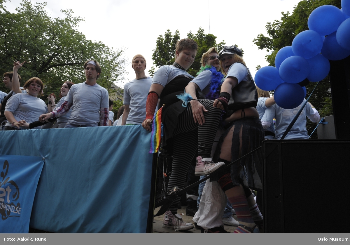Fotodokumentasjon av Homoparaden 2008. Mennesker, opptog, parade, kostymer, kjøretøy, tilskuere, bannere, paroler, parykker, sminke, dans, ballonger.