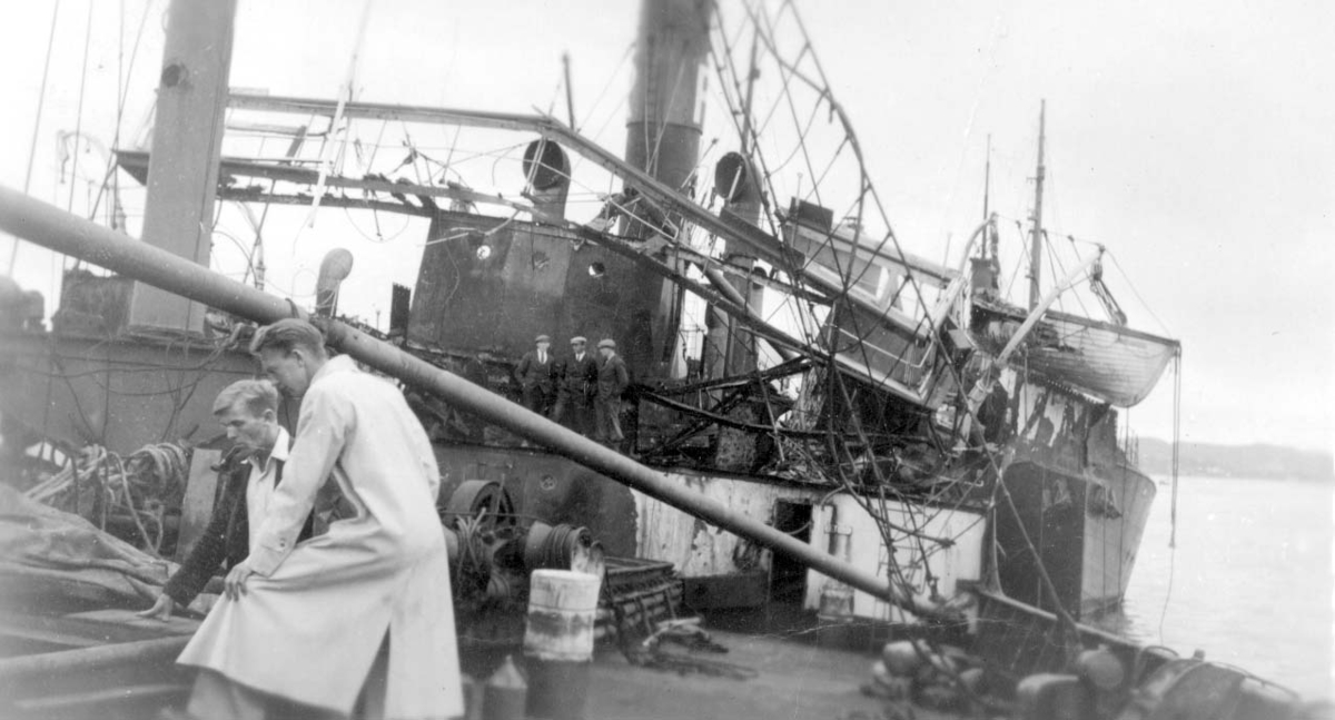 "Anna Sofie" på Risøyslippen. Istykkerbombet skip i dokk. Inspektører ser på skadene. Bak til h. annet skip - eskorteskip eller kansje krigsfartøy.