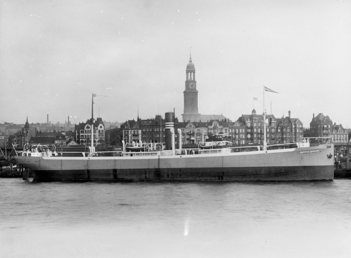 Dampskipet D/S "Valdemar Skogland" ankret opp ved en stor by.