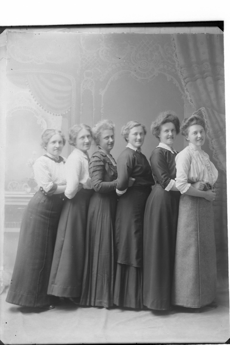 Studioportrett av seks kvinner på en rekke.