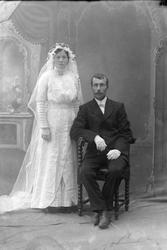 Studioportrett av et brudepar i helfigur.