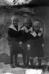 Studioportrett av tre barn stilt på en rekke.