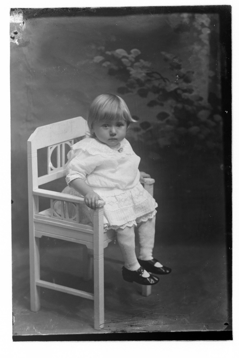 Studioportrett av et lite barn som sitter på en stol.