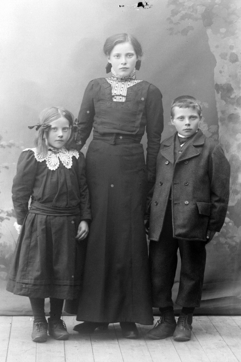 Studioportrett av en kvinne ved siden av to barn.