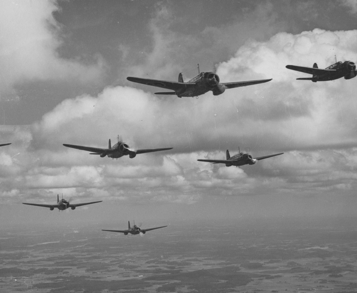 Sju stycken flygplan S 17 i formationsflygning i luften.