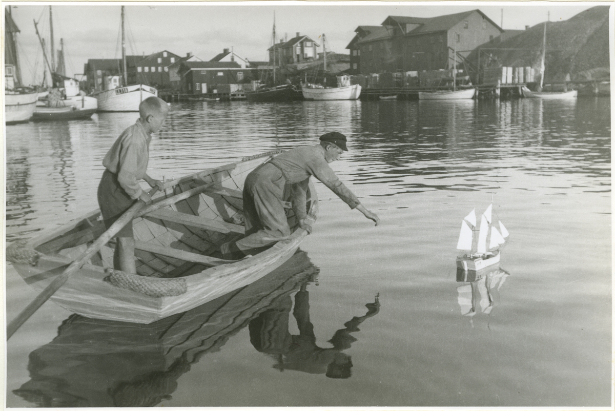 Fiskarpojkar lekande med båtmodell i Smögens hamn.