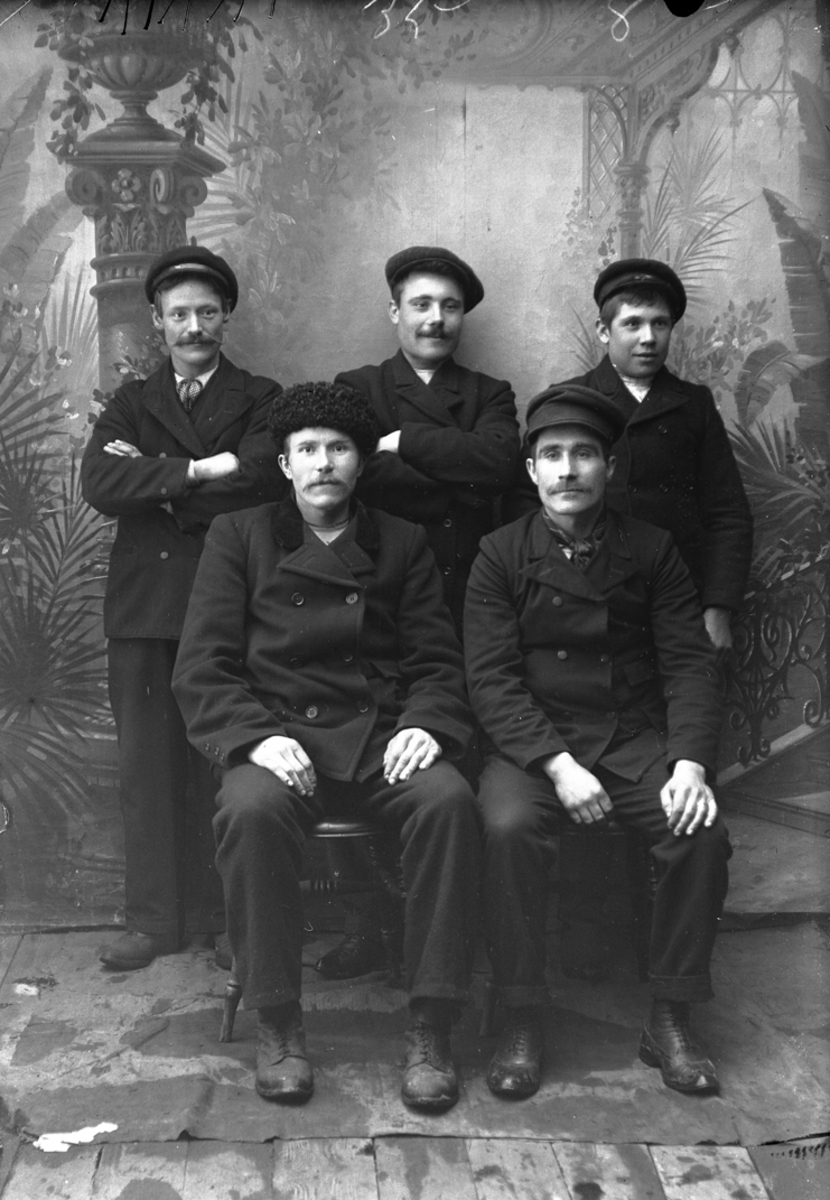 Portrett. 5 menn i 20-30-åra. To sitter - tre står bak. Luer.Bildet er tatt på Reine i Lofoten.