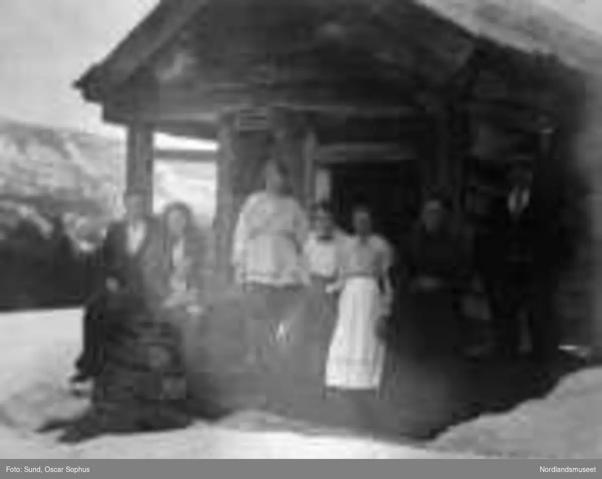 Skursdalen i Hol, Buskerud, Kleiva, 7 personer står ved trappa til "Lille-stabburet". Stabburet er tømret med en sval i forkant. Helt til venstre ses fiskerikonsulent Oscar Sund. Bildet tatt i påsken 1918.