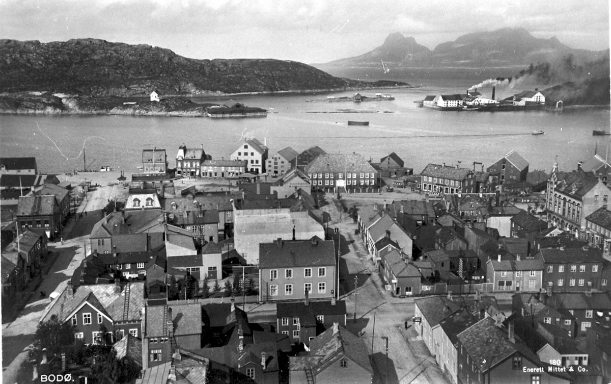 Tettsted - by. Bebyggelsen med havna i bakgrunnen. Settmot nordvest.
Foto: Prospektkort - Bodø by, ant. sett fra kirketårnet. Ladego i bakgrunnen.