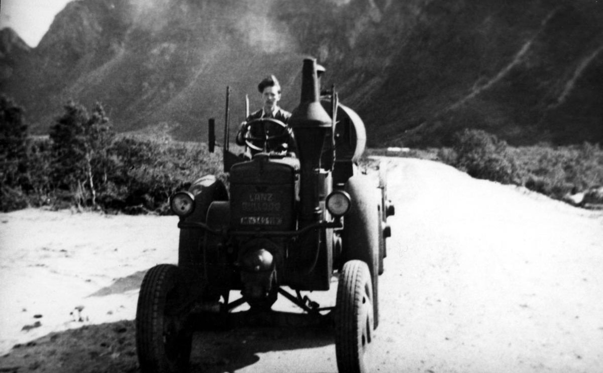 Portrett. 1 person, mann i militæruniform kjører en traktor, en Lanz Bulldog.
