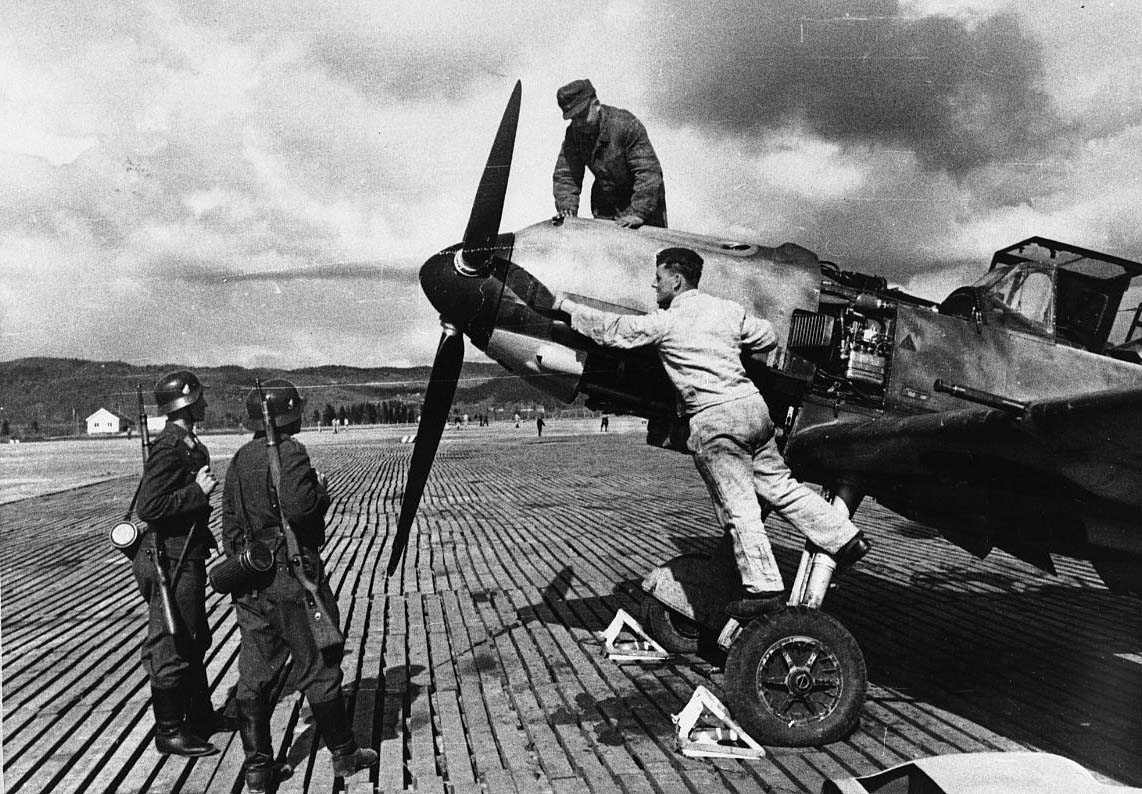 Lufthavn. tysk militert fly på bakken, Bf109. To vaktsoldater og to mekanikere ved flyet .