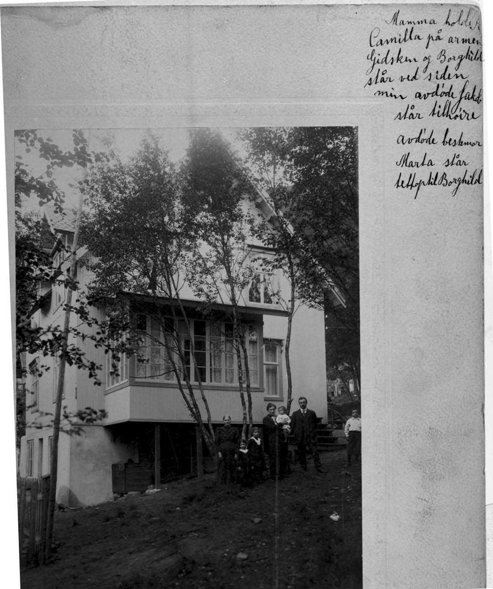Foto av sju personer foran ett hus. To kvinner, en mann og fire barn.