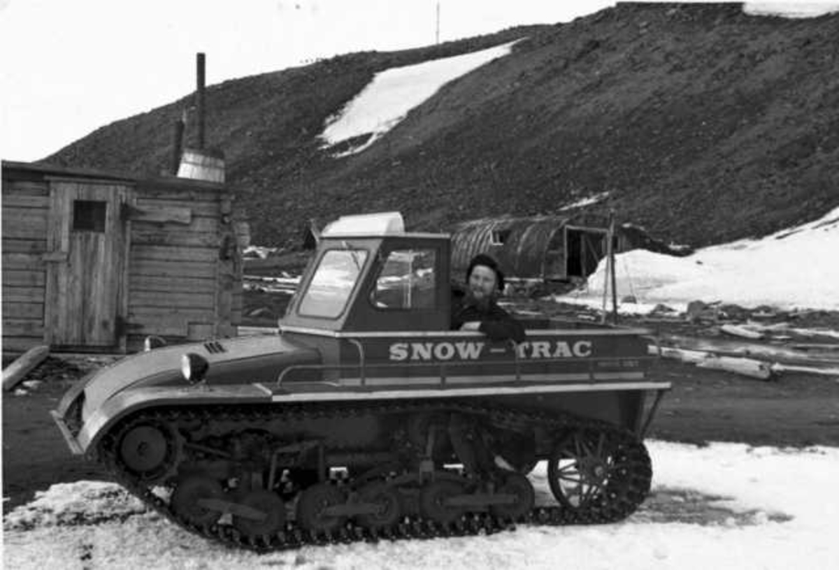 Beltekjøretøy, "Snow-Trac" ved ei bygning. En person, mann, i kjøretøyet.