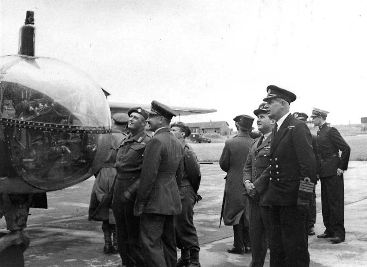 Flere personer som ser på et fly, bl.a. Kronrpins Olav.