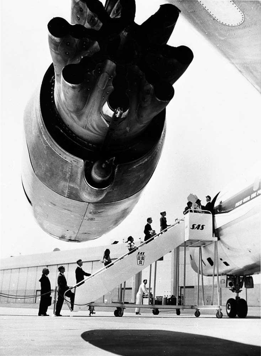 Lufthavn. Flere passasjerer på vei opp en flytrapp ombord i et fly, DC-8-33 OY-KTA "Dan Viking" fra SAS. Den ene motoren i forgrunnen.