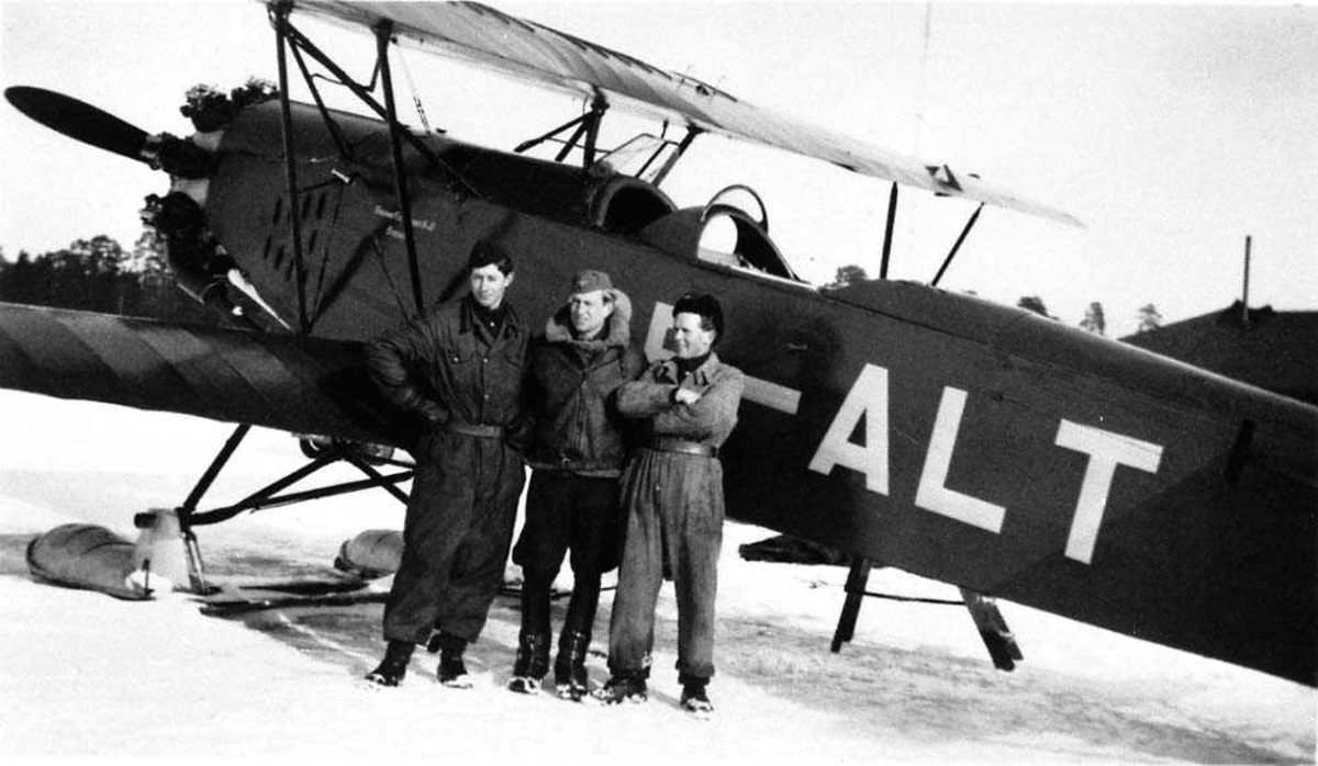Ett fly på isen, SE-ALT. Tre personer står ved flyet. Snø på bakken.