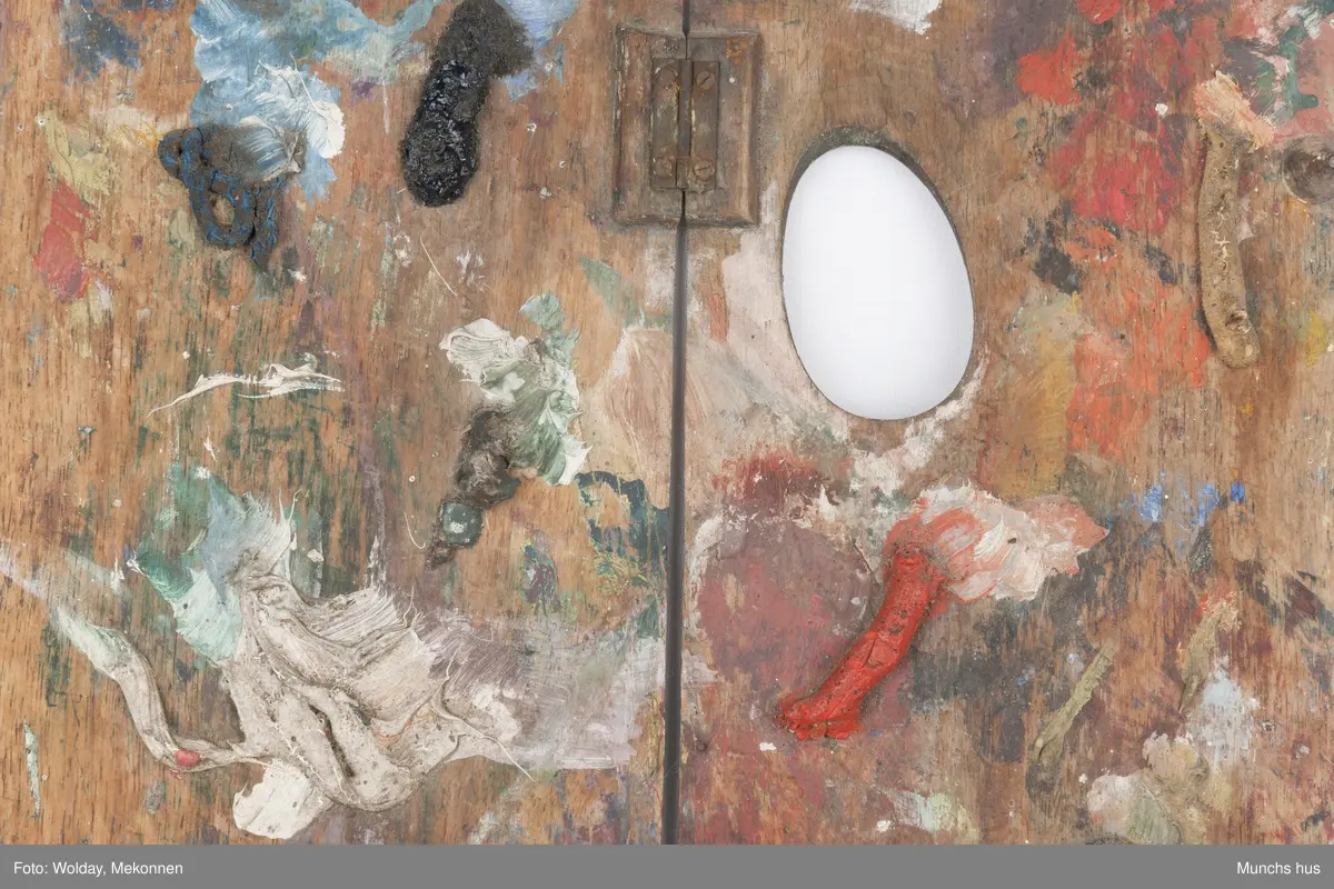 Malepalett i tre. Paletten er brukt og har mange spor av maling i ulike farger.