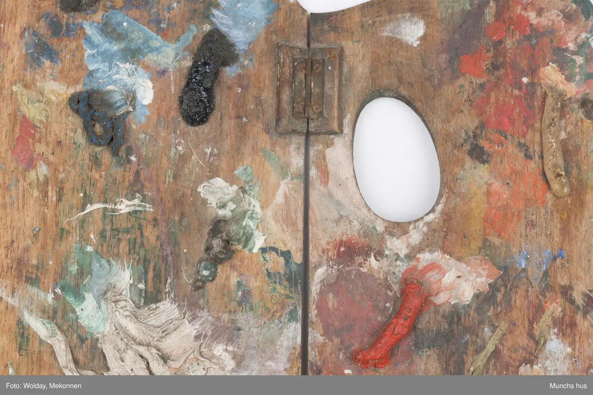 Malepalett i tre. Paletten er brukt og har mange spor av maling i ulike farger.