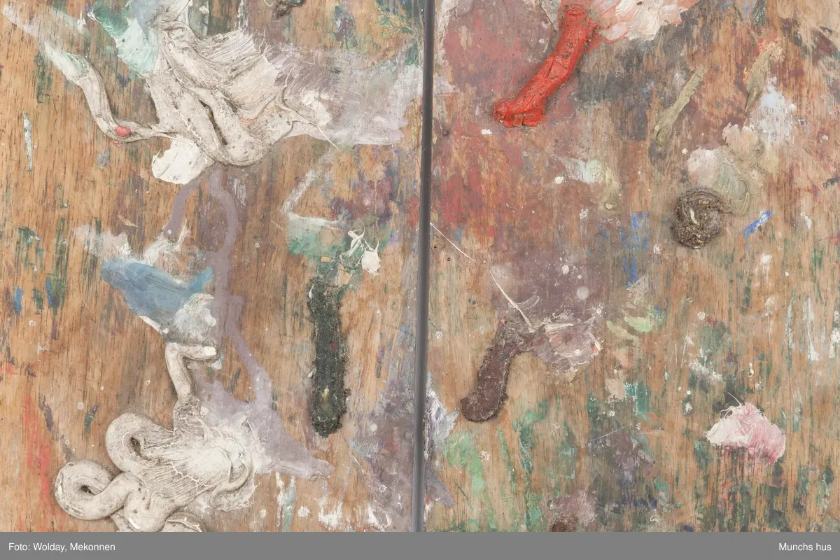 Malepalett i tre. Paletten er brukt og har mange spor av maling i ulike farger.