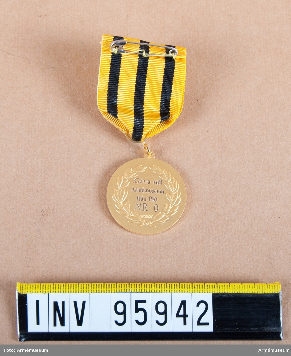 Södermanlands regementes (P 10) förtjänstmedalj i guld, före 2000 Södermanlands försvarsområdes (Fo 43), 8:e storleken.

Band: gult med tre jämt fördelade svarta ränder.

Medalj i blå ask klädd med blå sammet och vit siden.
