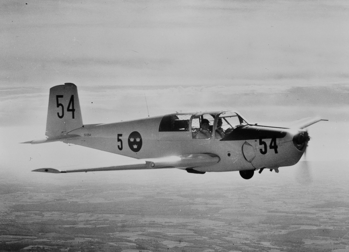 Flygplan SK 50B märkt nummer 54 (50054) från Krigsflygskolan F 5 flyger över landskap.