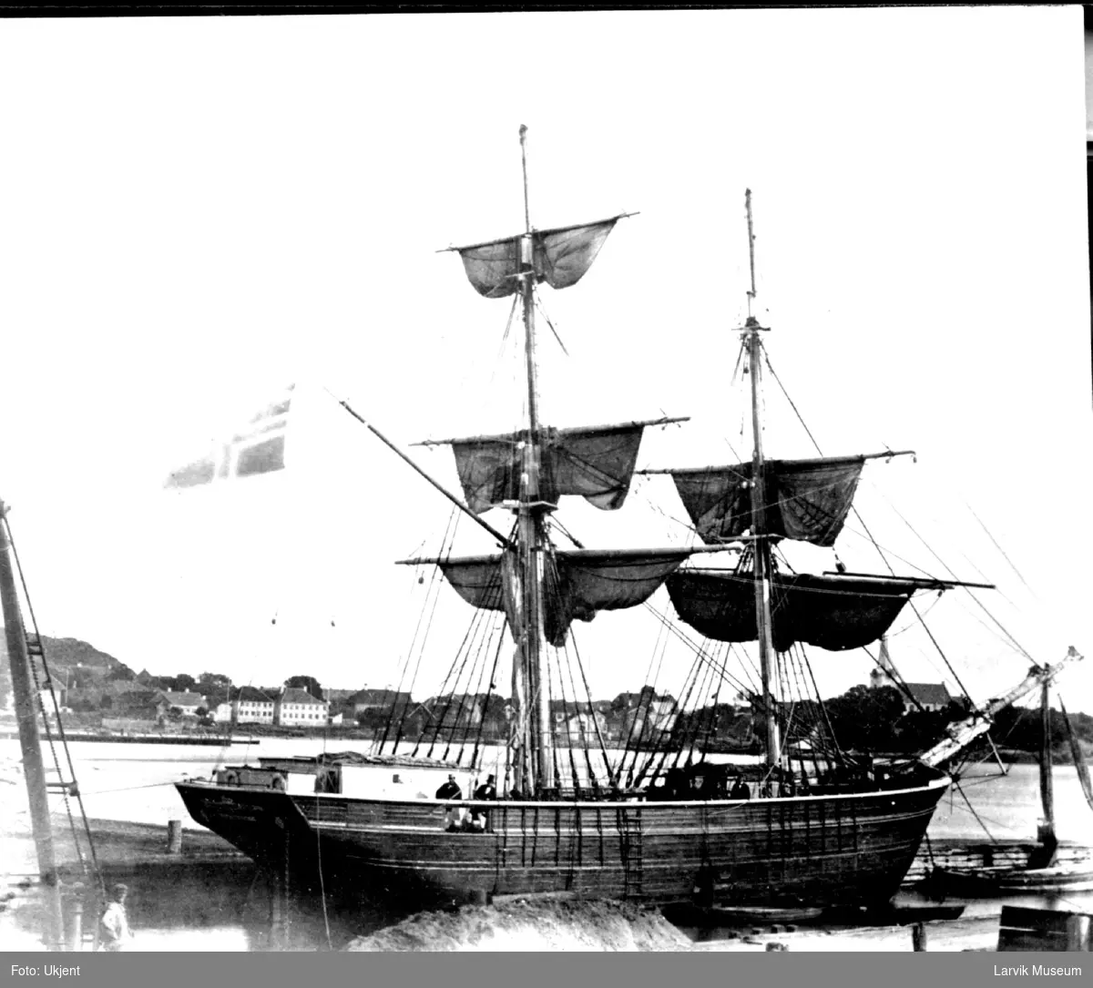 Fartøy, seilskip, sannsynlig brigg SCANDINAVIEN i Larvik havn, Tollerodden med Larvik kirke i bakgrunnen.