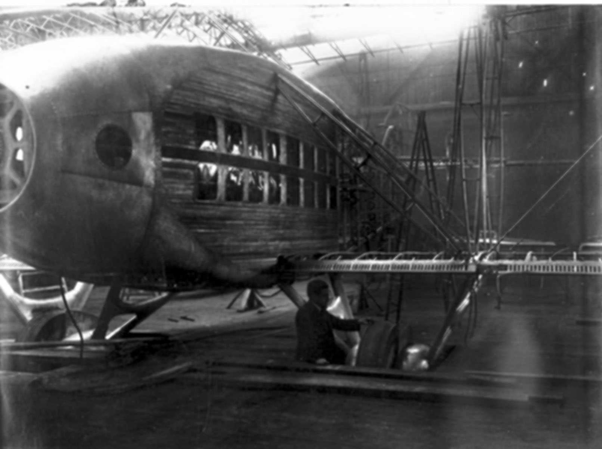 Ett fly inne i hangar eller lignende, under bygging, montering. Breguet Leviathan. En person ved flyet.