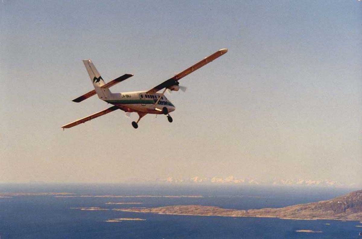 Luftfoto. Et fly, LN-BNJ, DHC-6 Twin Otter fra Widerøe, fotografert utenfor Bodø i forbindelse med åpningen av Norsk Luftfartsmuseum Bodø. Sørspissen av Landegode med Helligvær. Lofotfjellene i bakgrunnen.