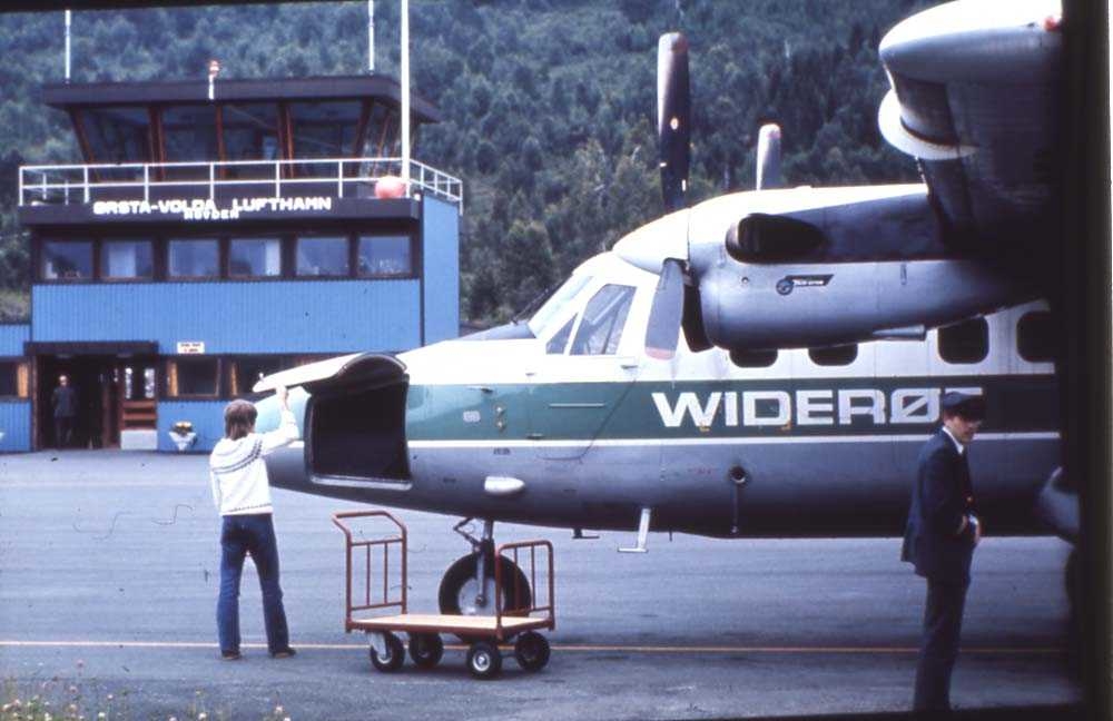 Lufthavn. Ørsta/Volda. Hovden. Et fly, LN-BNT, DHC-6-300 Twin Otter fra Widerøe parkert foran flytårn/ekspedisjon. 2 personer, en ekpeditør og en flyger/pilot foran flyet.