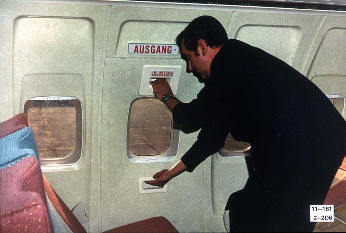 En person inne i kabinen på ett fly, Boeing 737-200, som åpner en nødutgangsdør.