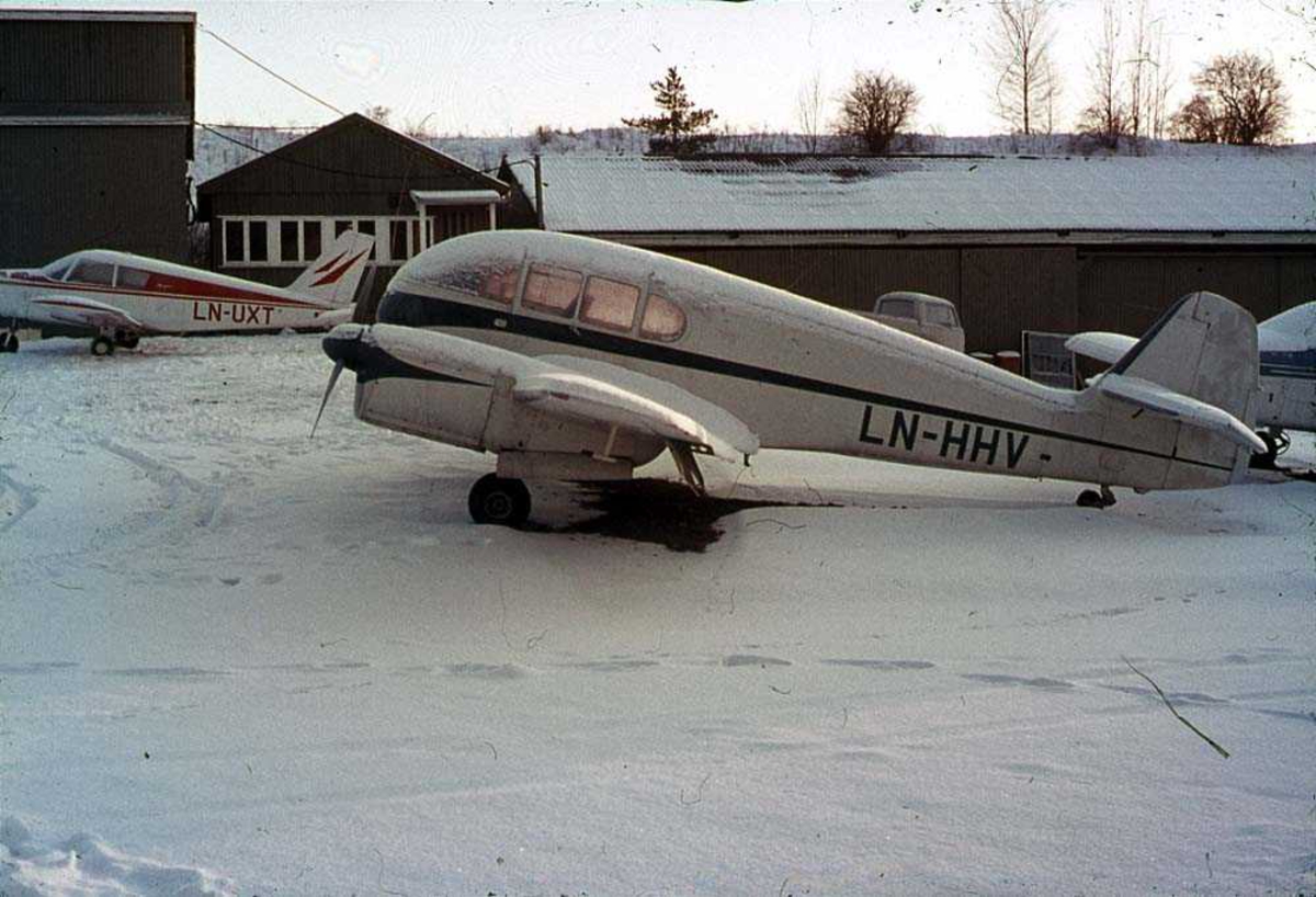 Ett fly på bakken, CZL Super Aero 45 LN-HHV. Bygninger og to fly i bakgrunnen. Snø på bakken.