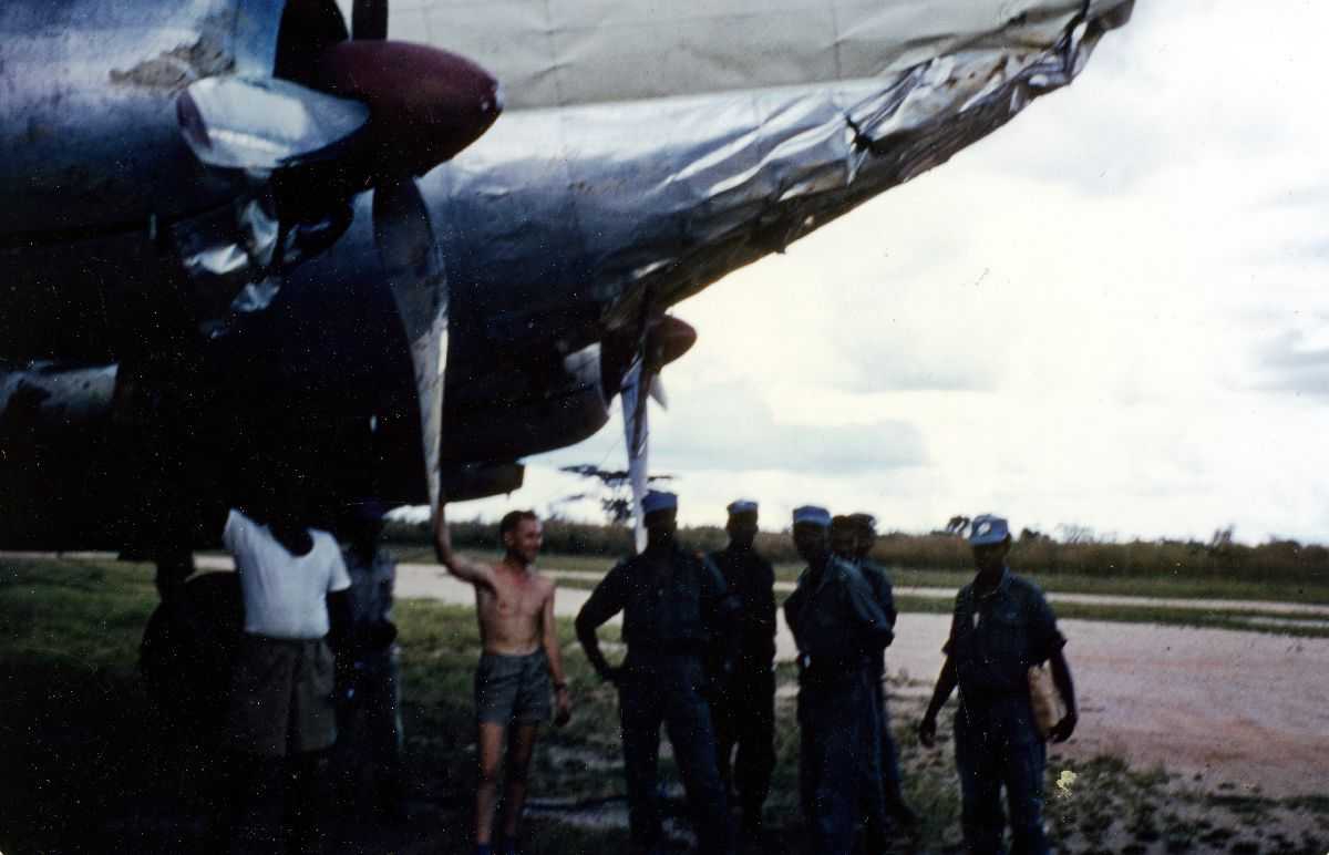 Ett fly på bakken med ødelagt neseparti, Curtiss C-46. Flere personer ved flyet.
