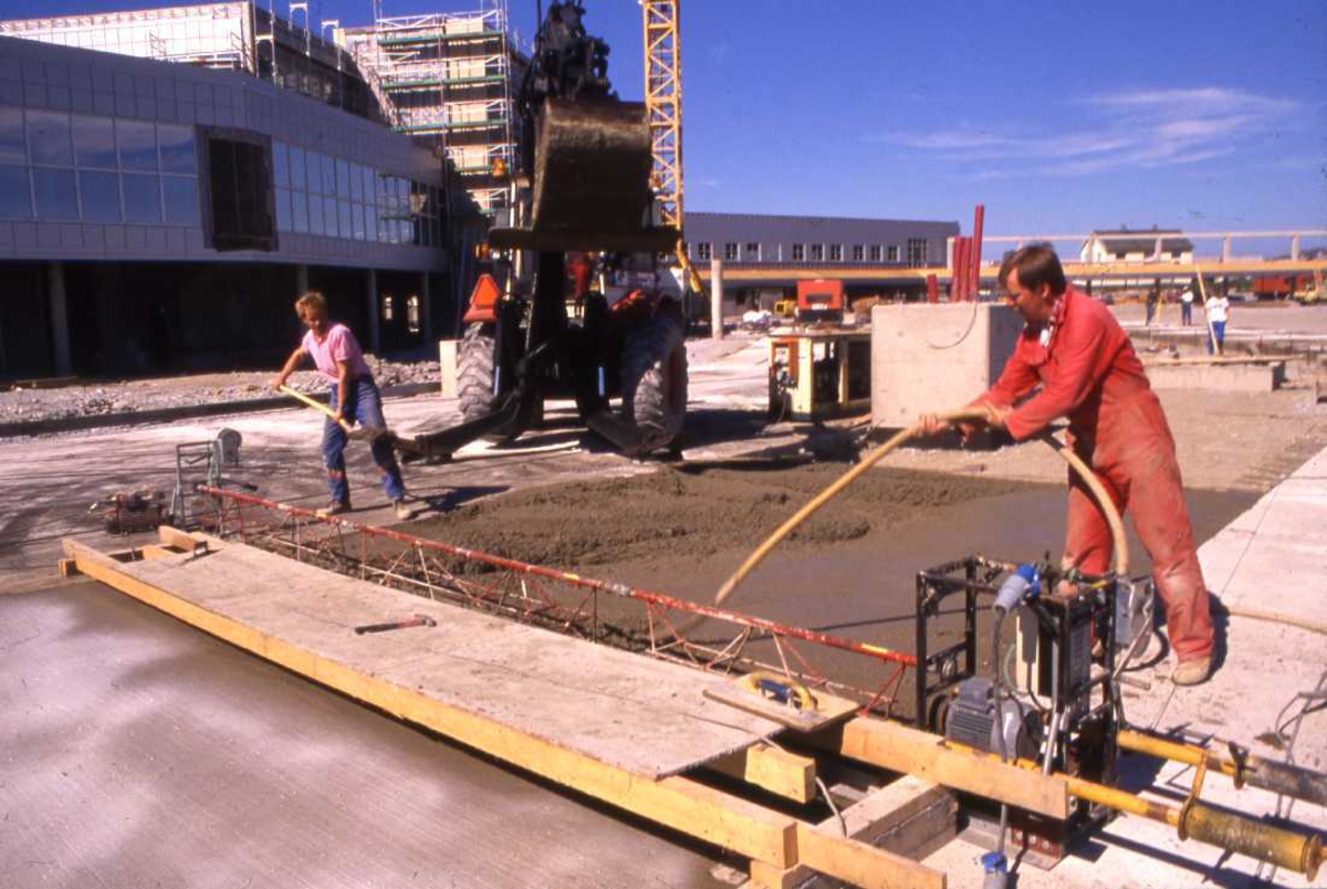 Lufthavn - flyplass. To personer legger betongdekke  på oppstillingsplassen for fly (tarmac)