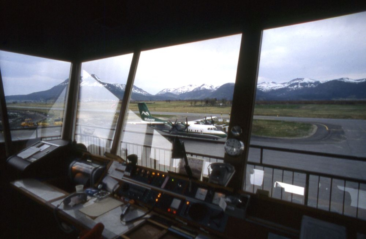 Lufthavn (flyplass). Fra flytårnet ser vi et fly, DHC-7-102, Dash7, fra Widerøe parkert. Litt av flystripa (runway) og fjell i bakgrunnen.