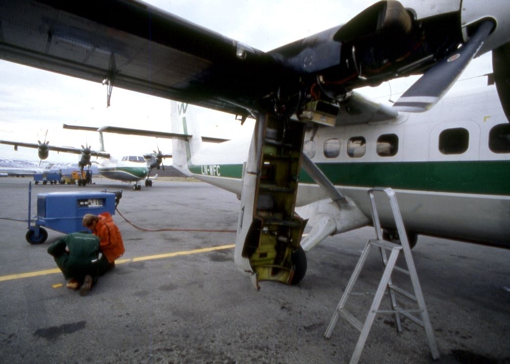Lufthavn (flyplass). To fly, LN-WFC, DHC-6-300 Twin Otter og en DHC-7-102 Dash 7 fra Widerøe. To flyteknikere i arbeid med høyre motor.