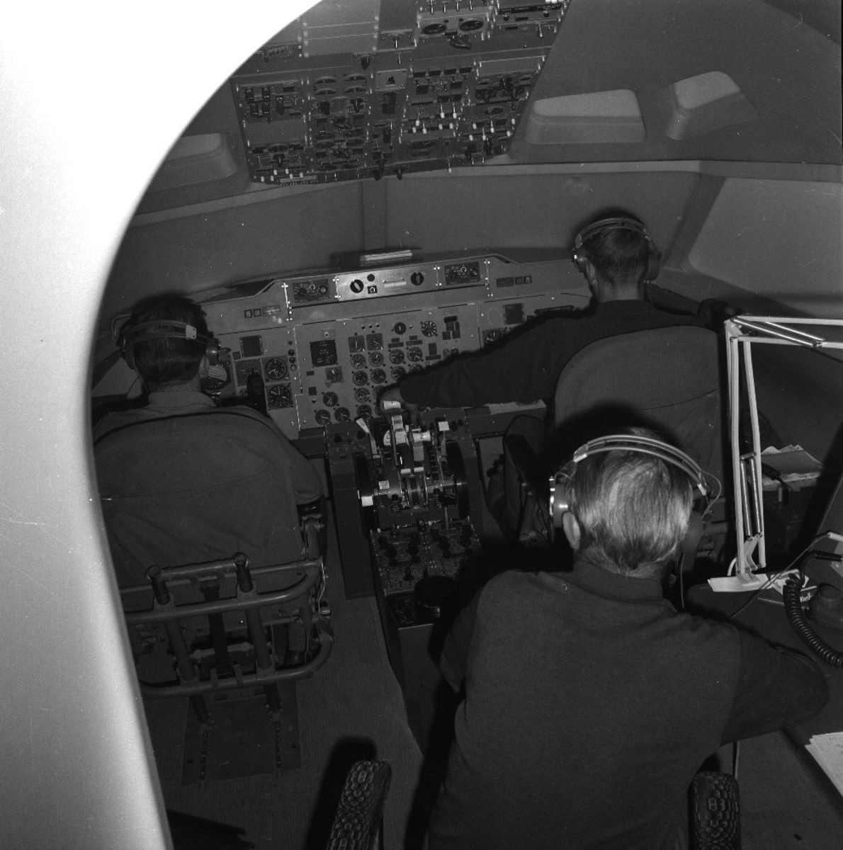 Treningssenter. To personer/piloter fra Braathens SAFE trener ferdigheter i en flysimulator. En person overvåker.