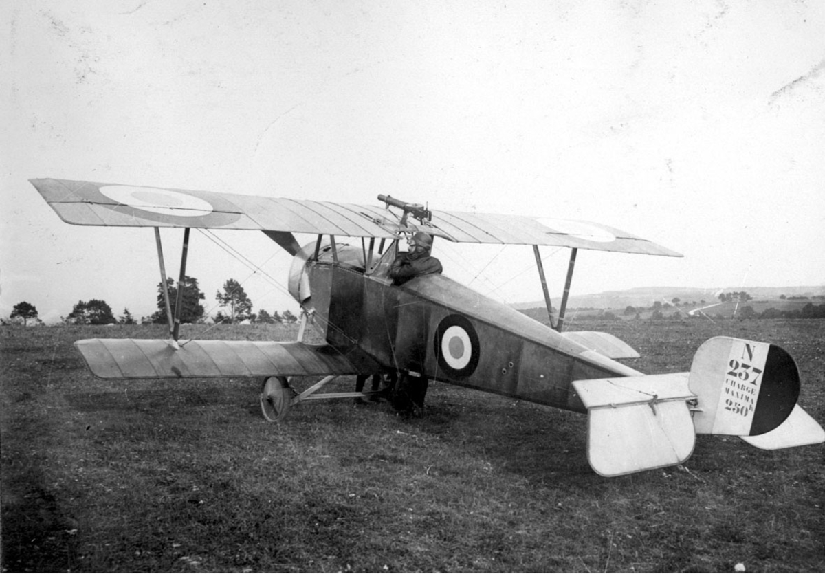Fly, Nieuport 11C.1 N 237. Skrått balfra. Står på bakken. 1 person, flyger, i cockpit. Våpen, maskingevær, montert på vingen over cockpit.