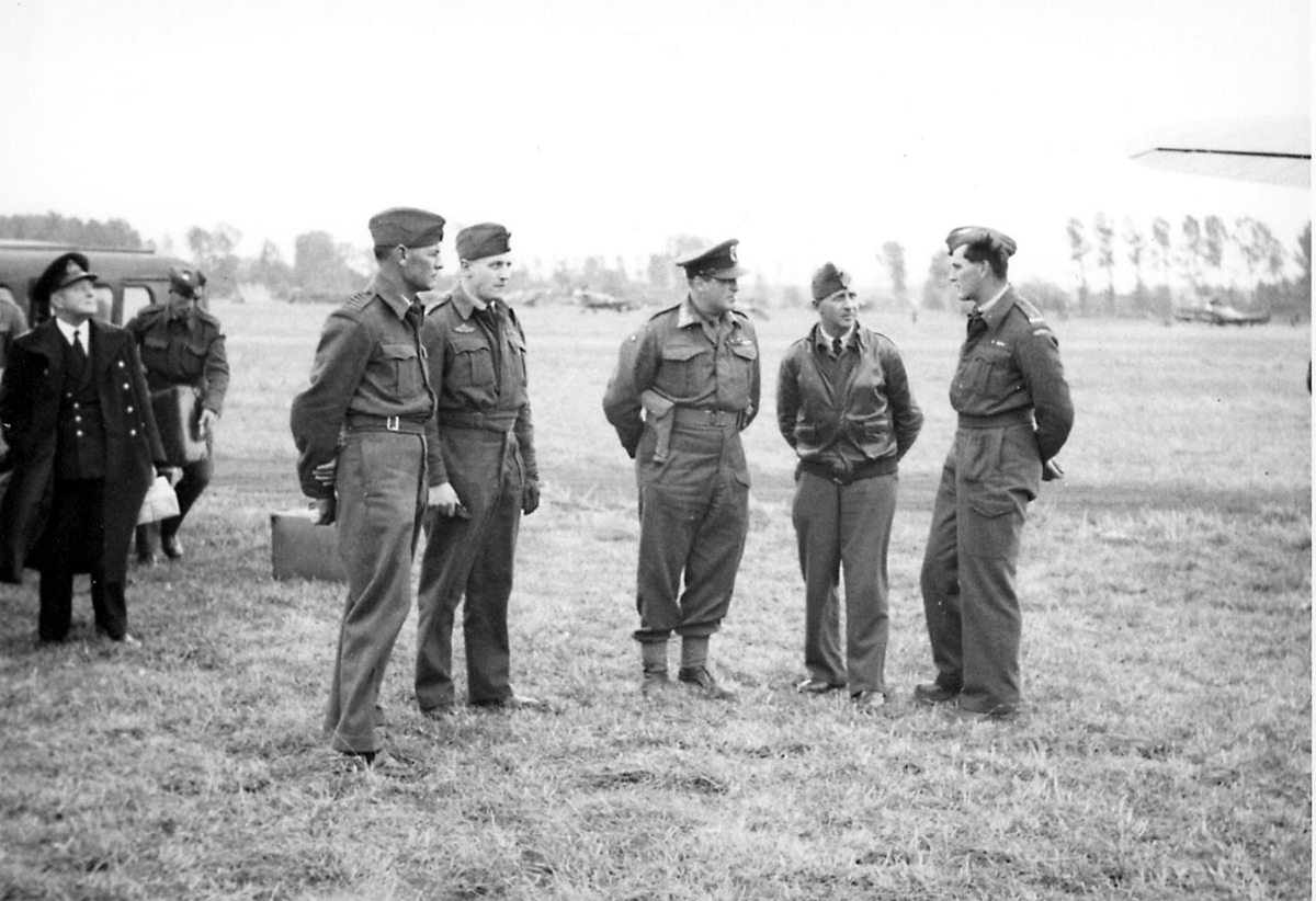 En gruppe personer, i militæruniform, tatt utendørs. Kronprins Olav i midten 