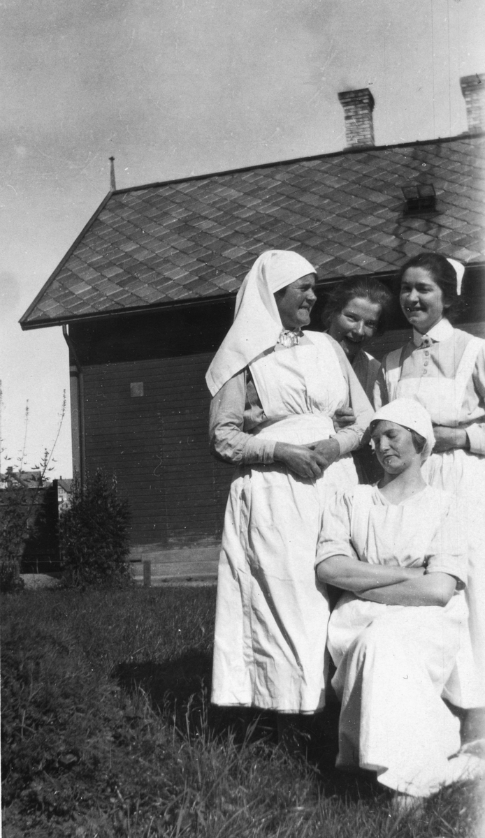 Sykepleiere og kokker (?) ved gamle Harstad sykehus, fotografert utendørs.