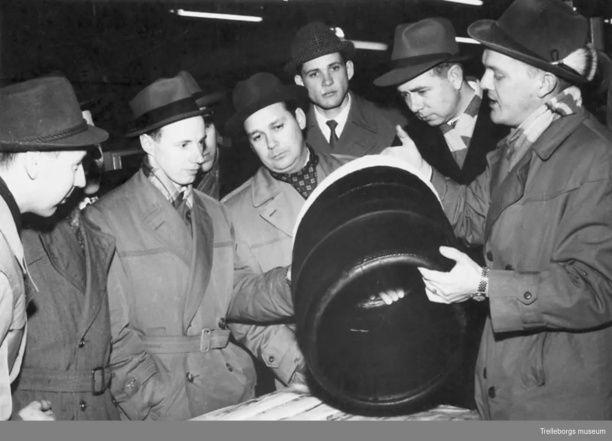 Besök av Malmöingenjörer i däckfabriken den 10 mars 1959. Docent Hans Palmgren (längst till höger) demonstrerar hur man lägger på en vit däcksida före vulkningen.