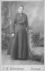 Portrett av ukjent kvinne. Hun er kledd i kjole med rutete o