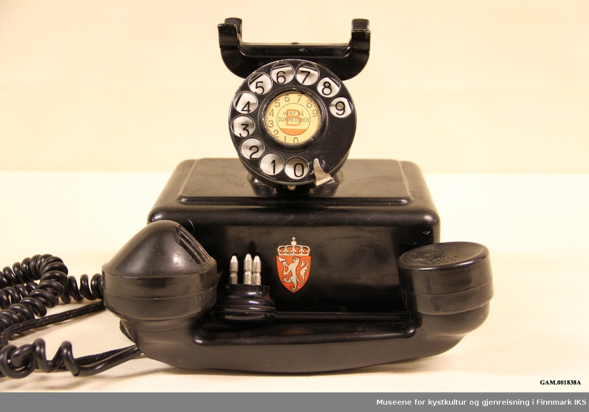 Telefonen er dekoret med Norges riksvåpen. I midten av tallskive det er trykket teksten "vent på summetonen."