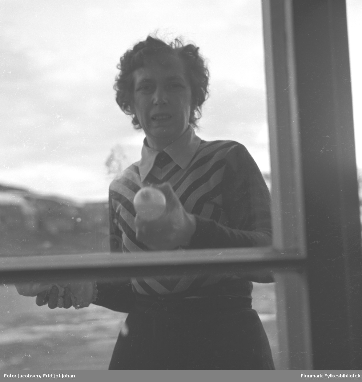 Karen Trondsen (Dalbom), fotografert i Nedre Grønnevoldsgate (i dag Strandgt.), i Hammerfest sentrum før 1940. Det er en fin vinterdag med sol, og fotografens skygge er synlig nede i høyre hjørne av bildet