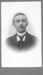 Portrett av ukjent mann. Han er kledt i mørk jakke, hvit skj