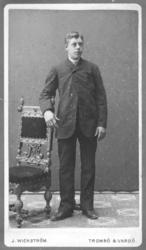 Portrett av ukjent mann tatt i et fotoatelier. Mannen er kle