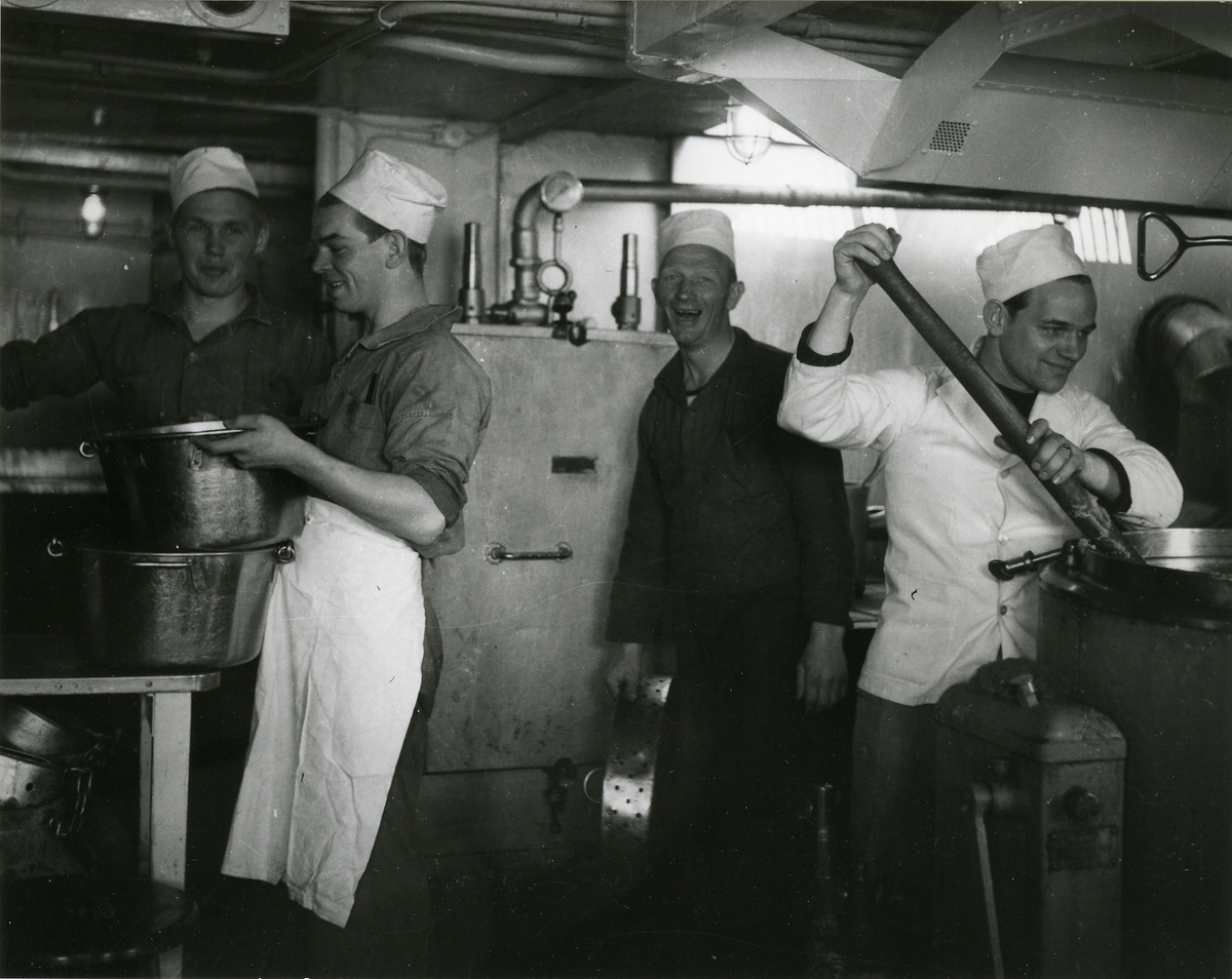 Personal i köket på ett örlogsfartyg arbetar med beredning av mat.