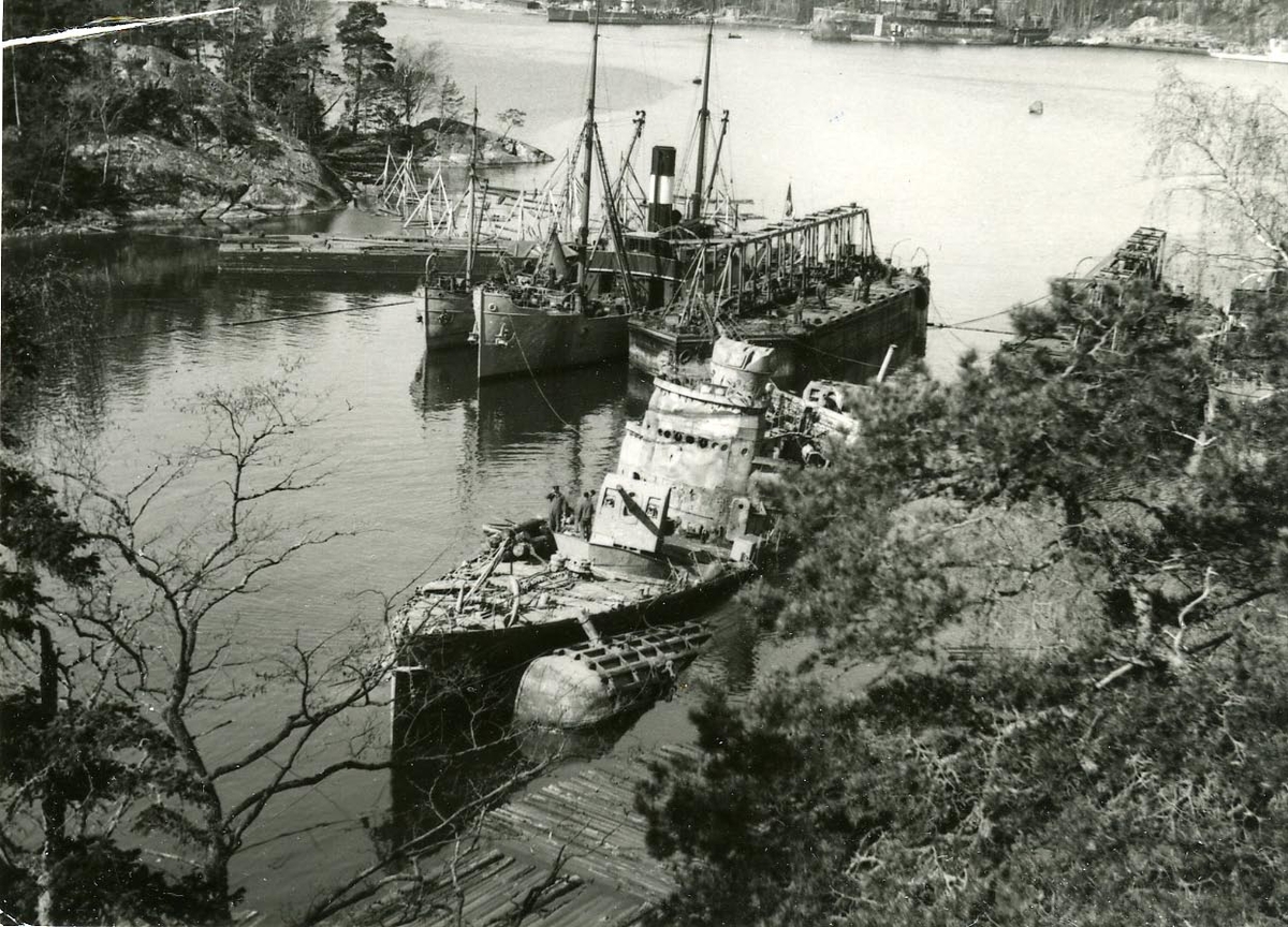 En av de vid olyckan den 17-9 1941 vid Hårsfjärden sjunkna jagarna bärgad och bogserad till land. I bakgrunden bärgningsfartygen.